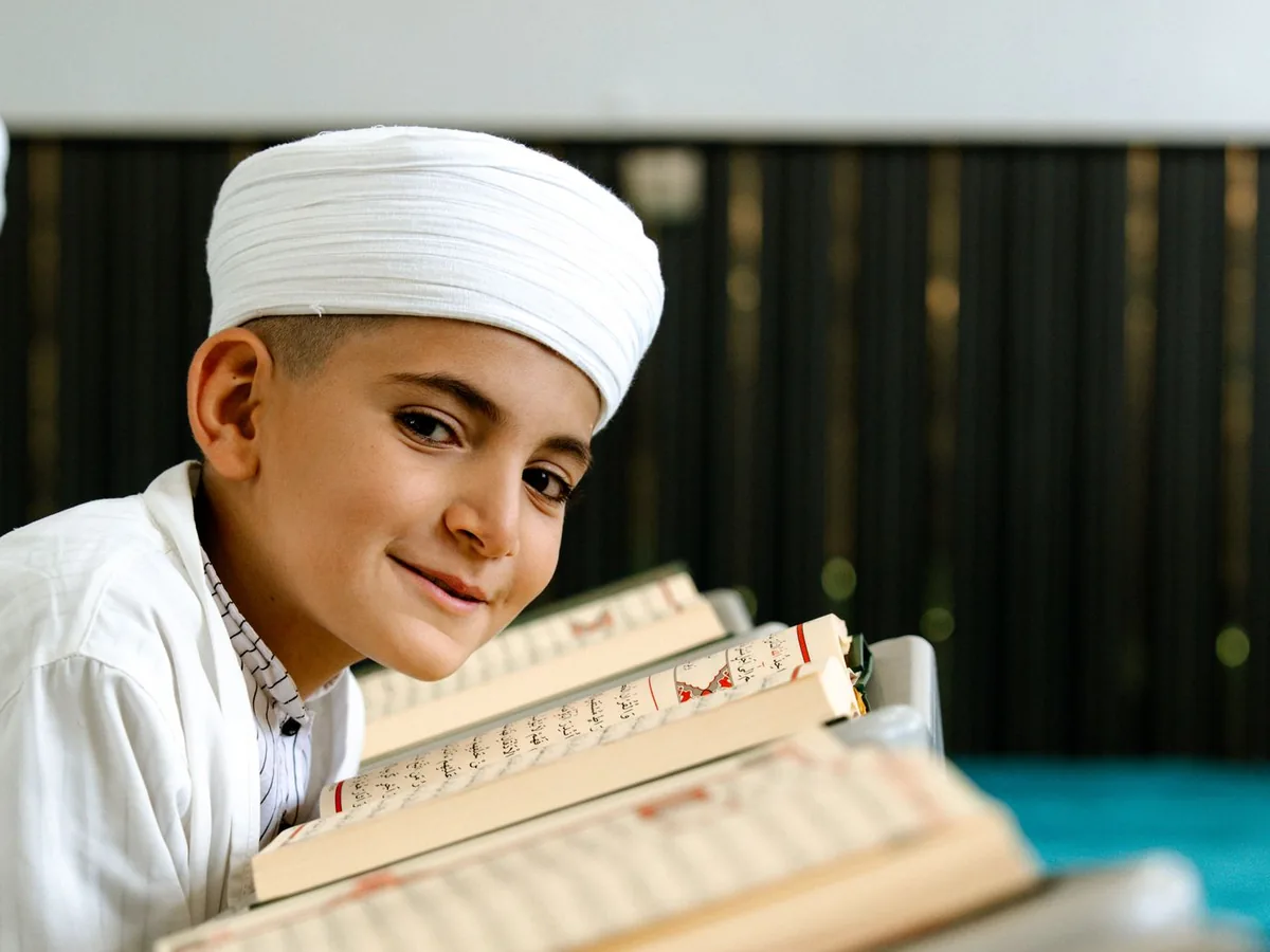 Smiling young Muslim boy with copies of the Holy Quran